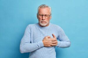 Senior man in spectacles presses hand to chest has heart attack suffers from unbearable pain closes